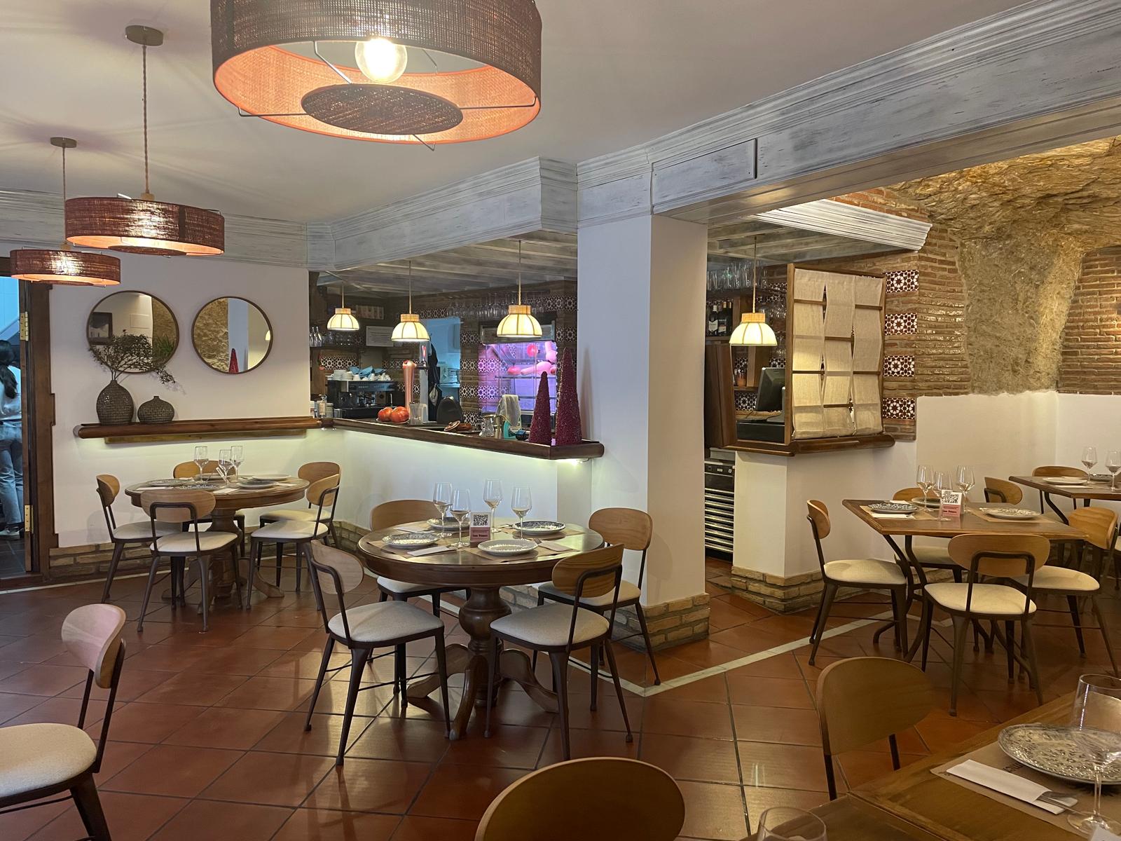 Comedor de Casa Palmero excavado en la roca, con mesas puestas y barra al fondo